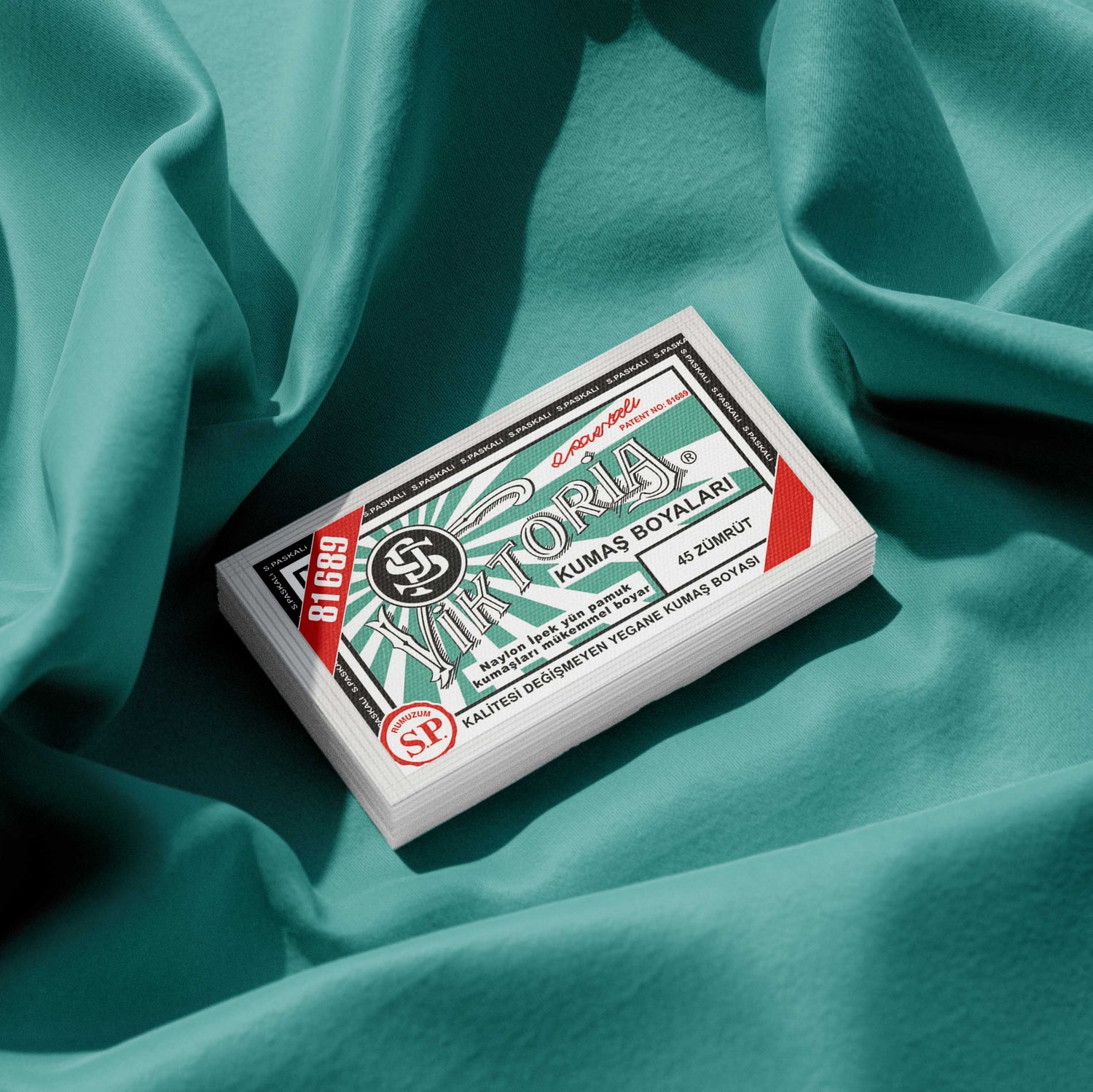 Pack of sea green fabric dye placed on a vibrant sea green fabric background